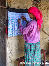 スカートのプリーツ加工のためしつけ糸を縫う白モン族の女性。