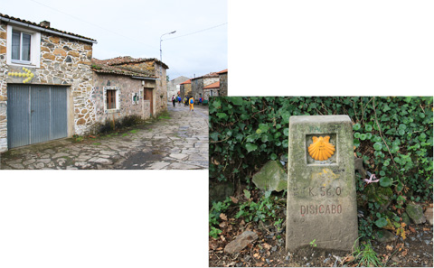 家壁に矢印があるレボレイロ村、巡礼路の中間地点を表すモホン